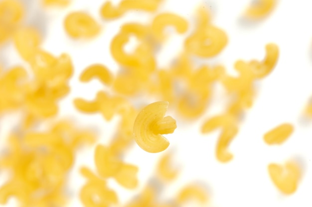 Macarrones volando explosión macarrones amarillos flote de pasta explotan mosca de nube abstracta macarrones curvas salpicaduras de pasta lanzando en el aire fondo blanco movimiento de congelación aislado enfoque selectivo