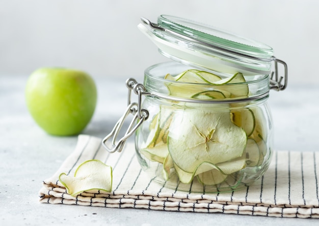 Maçãs desidratadas em frasco de vidro. lanche de frutas veganas