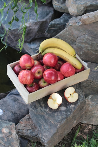 Maçãs e bananas em uma caixa no jardim