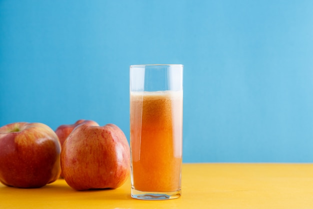 Maçãs e um copo de suco de maçã natural em amarelo-azul