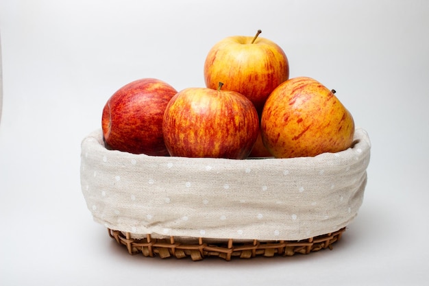 maçãs maduras em uma cesta de vime em um fundo branco