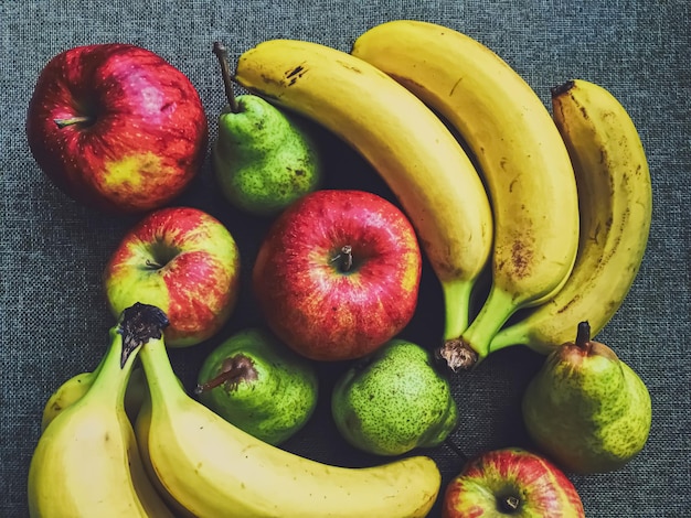 Maçãs orgânicas, peras e bananas em fundo de linho rústico