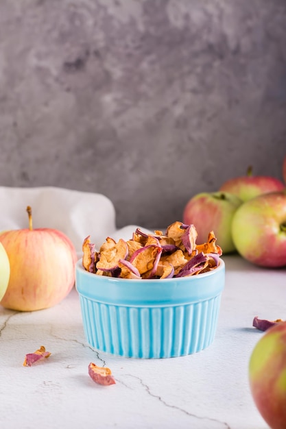 Maçãs secas fatiadas em uma tigela e frutas frescas na mesa Lanche caseiro Vista vertical