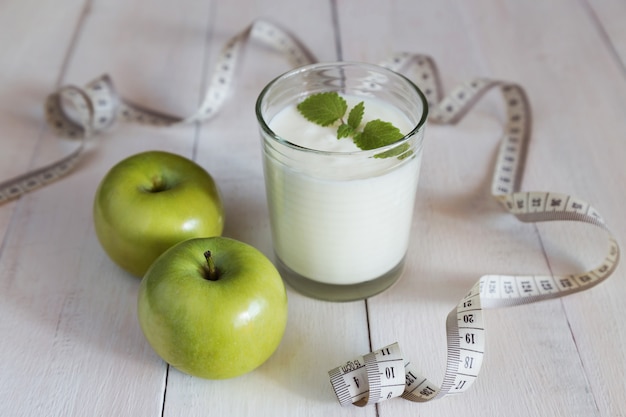 Foto maçãs verdes, copo de iogurte e fita métrica