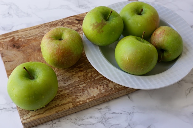 maçãs verdes e saudáveis em um prato branco na mesa da cozinha