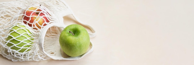 Maçãs verdes e vermelhas em uma bolsa ecológica de malha