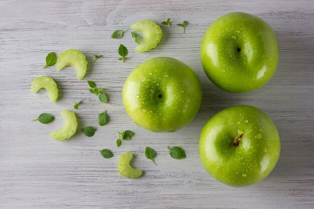 Maçãs verdes frescas e algumas folhas de manjericão na mesa de madeira