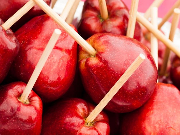 Maçãs vermelhas com palito pronto para serem mergulhadas no caramelo.