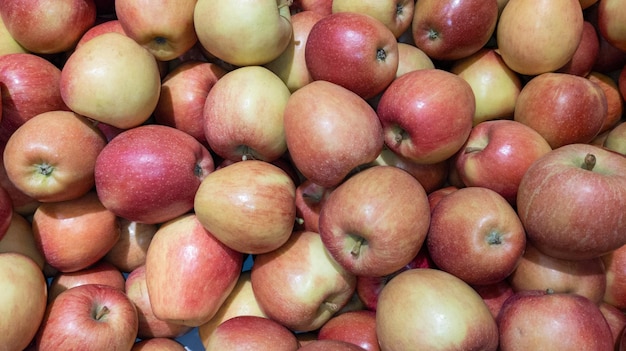 Maçãs vermelhas, muitas pilhas suculentas e maduras de frutas frescas de maçã como pano de fundo