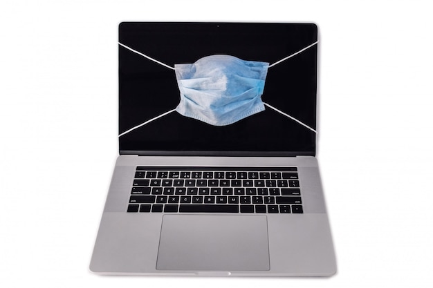 MacBook como computadora portátil con máscara facial que muestra protección en el trabajo a domicilio remoto en cuarentena