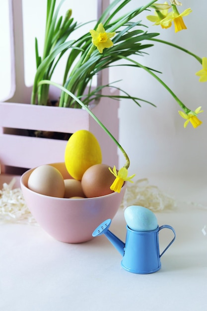 Maceta de huevos de Pascua con narcisos amarillos florecientes y decoraciones para el hogar