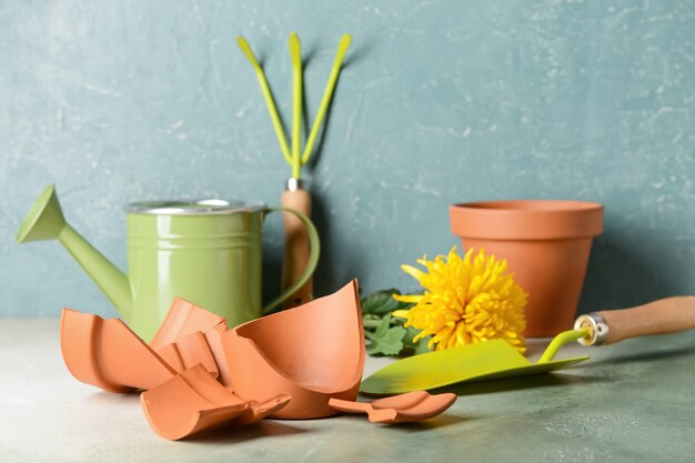 Maceta rota y herramientas de jardinería en la mesa