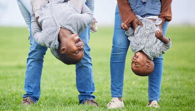 Mach alles, aber lass es Freude machen Aufnahme von zwei Kindern, die kopfüber von ihren Eltern draußen hängen