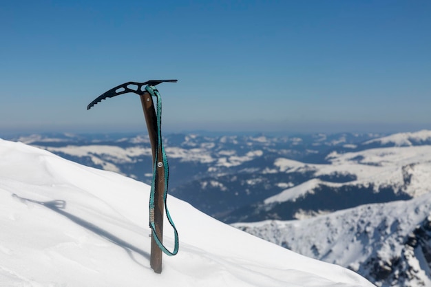 Machado de gelo do alpinista preso em uma encosta de neve alpinismo de inverno