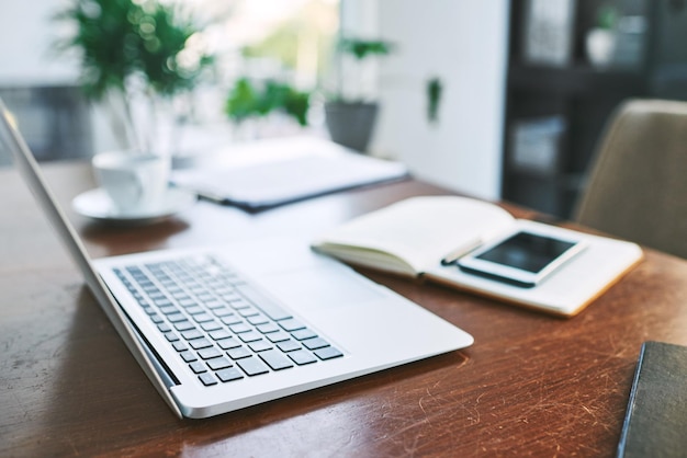 Machen wir uns dann an die Arbeit. Stilllebenaufnahme eines Laptops, Notebooks und eines Mobiltelefons auf einem Tisch in einem Büro