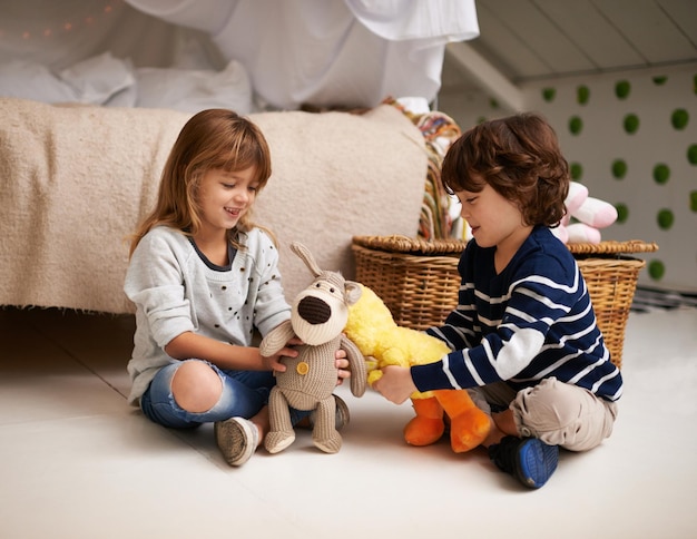 Machen wir unseren eigenen Streichelzoo. Aufnahme von zwei entzückenden Geschwistern, die zusammen mit ihren Kuscheltieren spielen