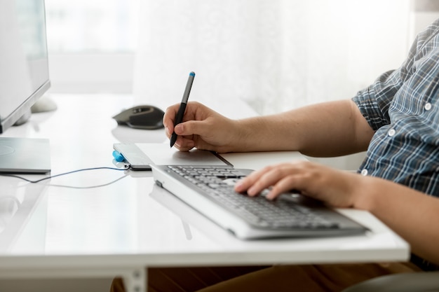 Macho adulto joven está woking en su escritorio