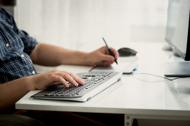 Foto macho adulto joven está woking en su escritorio