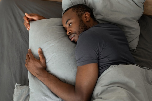 Macho africano cansado deitado com insônia no quarto alto ângulo