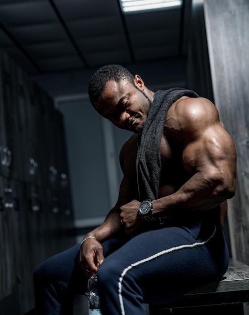 Macho africano perfecto muscular en vestuario. Hombre que descansa después de un entrenamiento pesado. Retrato.