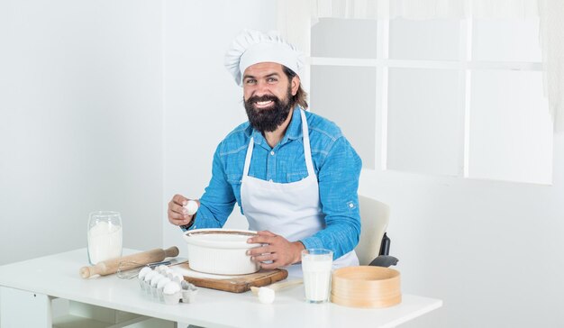 macho brutal com bigode e barba no avental cozinhando refeição, cozinha.