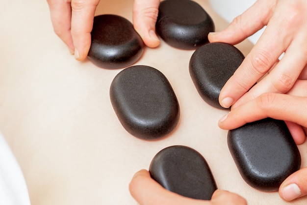 Foto macho cuatro manos poniendo piedras en la espalda femenina