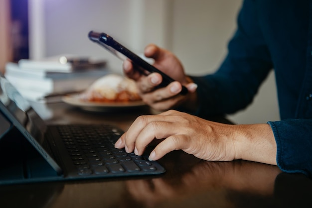 Macho está usando um tablet de conexão wi-fi de celular na mesa com uma xícara de café pela manhã