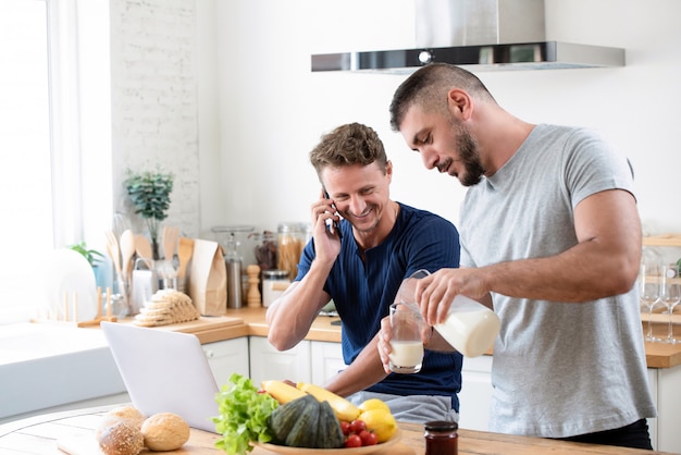 Macho gay feliz preparando o café da manhã para seu parceiro em casa