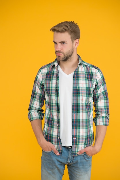 Macho guapo. moda casual para hombres. Look y atuendos masculinos. hombre con estilo en ropa de moda. guapo en jeans y camisa a cuadros. estudiante fondo amarillo. Te hace lucir bien.