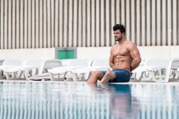 Macho jovem olhando na piscina ao ar livre