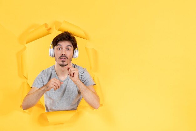 Macho joven en auriculares sobre papel amarillo sonidos de ultrasonido de audio de fondo