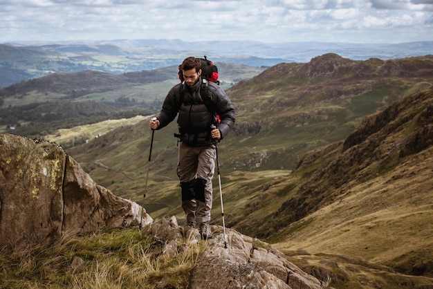 Macho joven excursionista subiendo la montaña El Lake District Cumbria Reino Unido