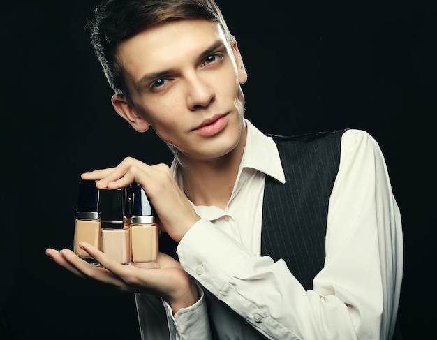 Foto macho joven maquillador posando con base para maquillaje o