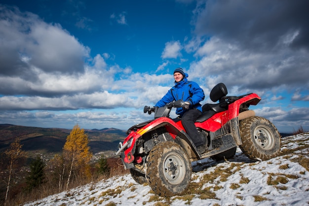 Macho no quadrilátero descendo a encosta nevado em dia ensolarado