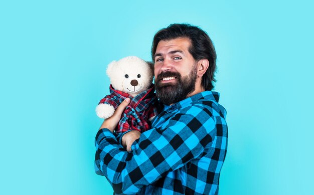 Macho segurando aniversário ou dia dos namorados presente homem barbudo de camisa quadriculada segurar ursinho de pelúcia cara casual expressar emoções de amor feliz hipster com brinquedo de bigode