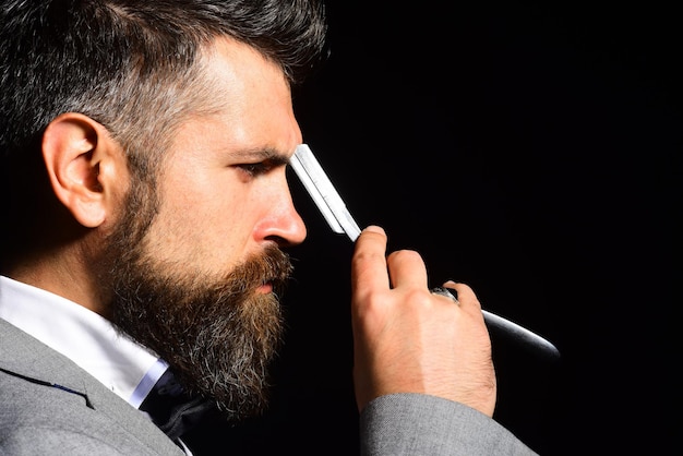 Macho en traje formal se afeita la barba Empresario con rostro serio