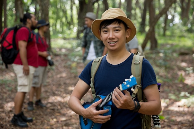 Macho con ukelele caminando al bosque