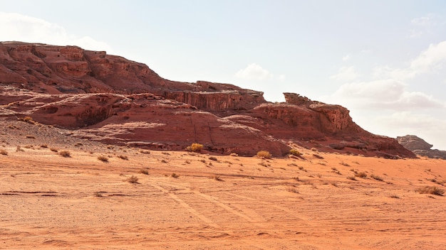 Macizos rocosos en el desierto de arena roja, cielo nublado brillante en el fondo - paisaje típico en Wadi Rum, Jordania.