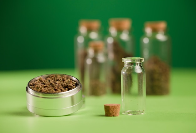 maconha picada em um moedor e potes de vidro herméticos com diferentes tipos de cannabis