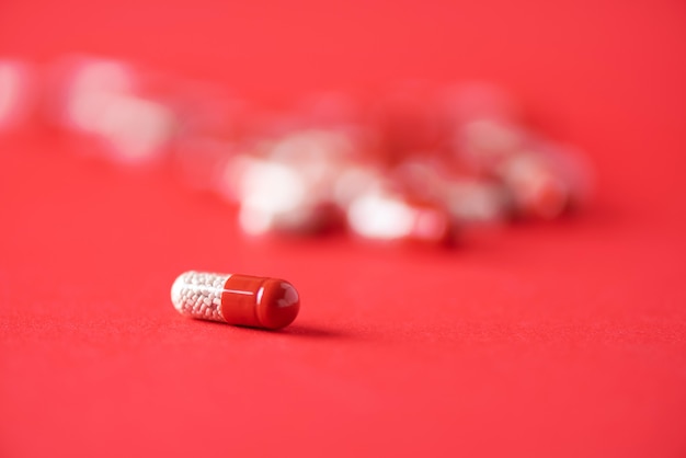 Macro de cápsulas rojas sobre fondo rojo. Copia espacio Montón de drogas, tratamiento para la gripe fría.