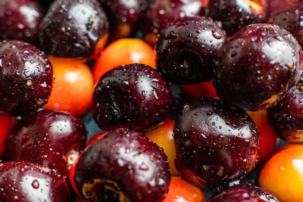 Macro de cerca de cerezas multicolores con gotas de agua sobre ellos