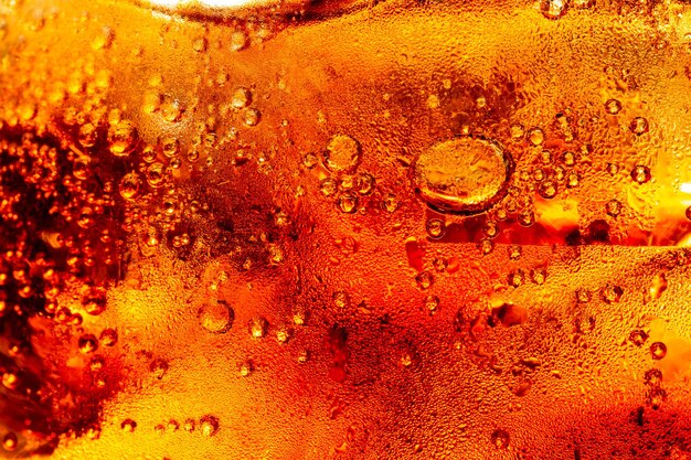 Macro cola Detalle de refresco carbonatado burbujeante frío con hielo Vista de cerca de los cubitos de hielo