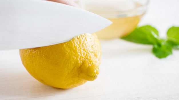 Macro de cuchillo afilado cortando limón maduro en blanco