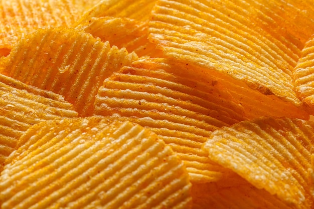 Macro de belos chips amarelos corrugados sob os raios do sol