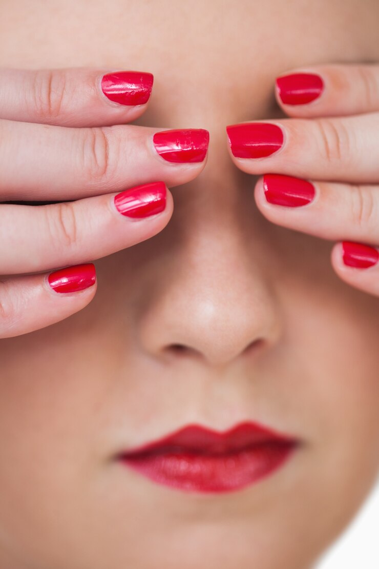 Foto macro foto de jovem mulher cobrindo os olhos com as unhas pintadas de vermelho