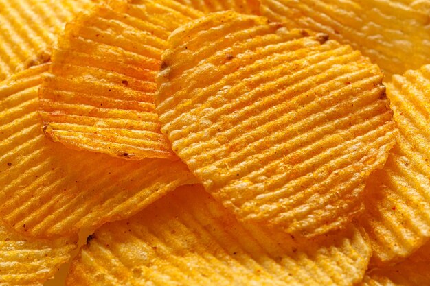 Macro de hermosos chips amarillos corrugados bajo los rayos del sol