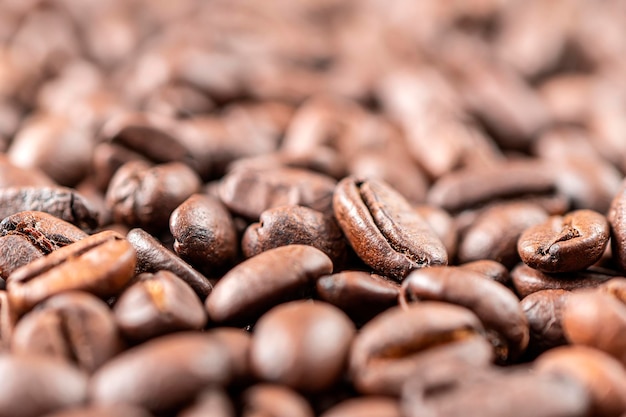 Macro de primer plano un grupo de granos de café tostados marrones o negros de fondo
