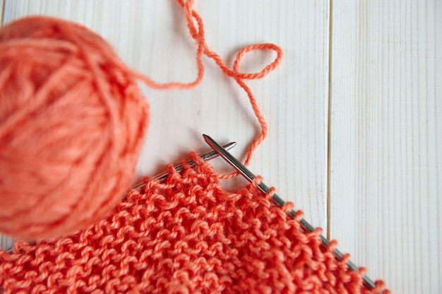 Madeja de hilo rojo de lana, con agujas para tejer a mano sobre una mesa de madera