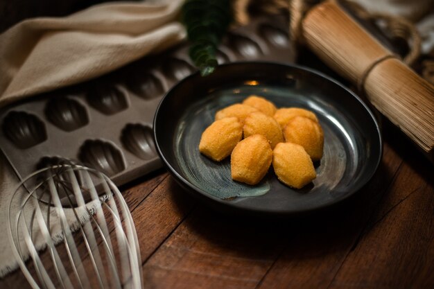 Madeleine con plato de cerámica sobre una mesa de madera