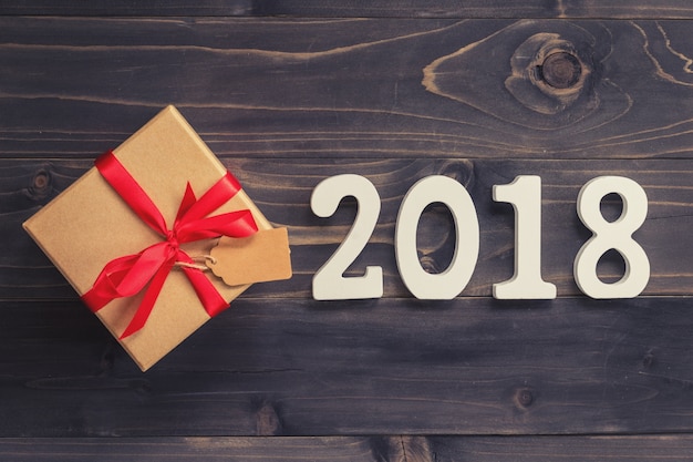Madera números 2018, Para el nuevo año 2018 sobre fondo de madera rústica con caja de regalo y cinta roja.